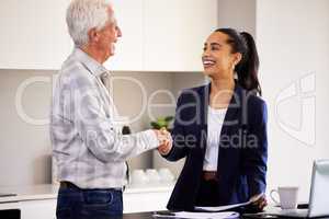 Its always great to see you. an attractive young female broker and a senior male client shaking hands during a meeting in his home.