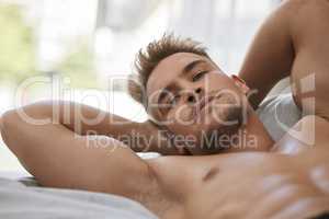 Looking buff in bed. Cropped portrait of a handsome and muscular young man lying in his bed at home.