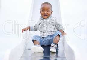 Theres no fear when youre having fun. a baby boy playing on the slide in the park.