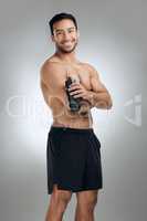 Exercise is always a good idea. an athletic man holding a bottle of water while standing against a grey background.