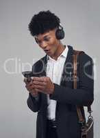Turn it up and let the music work its magic. Studio shot of a young businessman using a smartphone and headphones against a grey background.