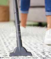 Getting all that pet hair out. an unrecognizable woman standing and using a vacuum to clean her carpet at home.