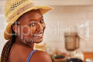 Ive learned to be as alone as together means. Portrait of a beautiful young woman wearing a sunhat in the kitchen at home.