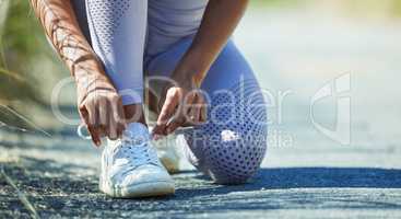 Gearing up to tackle a tough path. Closeup shot of an unrecognisable woman tying her shoelaces while exercising outdoors.