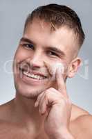 Just another day in the maze of a myth. Cropped closeup portrait of an attractive young man applying moisturiser to his face against a grey background.