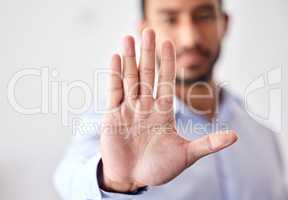 Closeup of the hand of a business man showing stop, saying no or not accepting a deal in an office at work. Male corporate worker making hand gesture not agreeing to a statement or refusing an answer