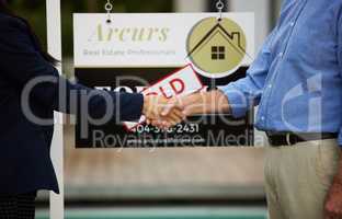 Concluding the deal with a handshake. Cropped portrait of an unrecognizable female real estate agent and her male client shaking hands in front of a sold sign in front of a newly purchased home.