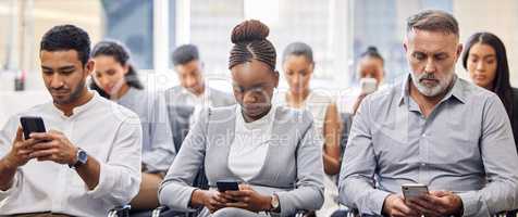 Connected, 247. a group of businesspeople using their cellphones while sitting in the office during a conference.