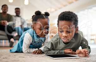 Say goodbye to bored kids with entertaining ebooks. an adorable little boy and girl using a digital tablet with their family in the background at home.