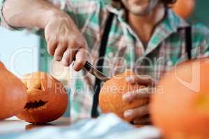 Carving the perfect pumpkin is a skill. a young man carving a pumpkin at home.