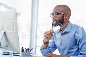 Im sure I can solve this one. a businessman looking thoughtful while sitting at his desk.