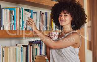 Summon me for glory. Portrait of an attractive young woman browsing a book shelf at home.