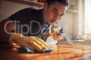 Clean your cares away. a young man disinfecting a kitchen counter at home.