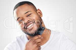 A daily grooming routine helps to maintain your personal hygiene. Studio portrait of a handsome young man brushing his facial hair against a white background.