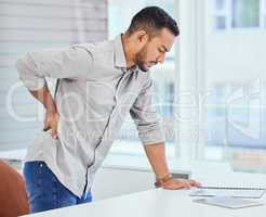 Someone needs to get me a masseuse. a young businessman experiencing back pain at the office.