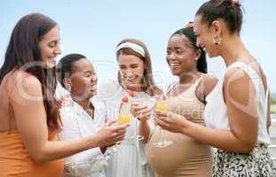 Cheers to you and your little one. a group of female friends toasting to their pregnant friend at a baby shower.