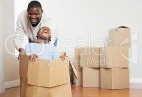 Dad knows how to make me laugh. a happy young father bonding with his daughter and pushing her in a box in their new home.