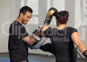 Kickboxing is such an exhilarating, calorie-burning cardio workout. a young man training a client in a boxing gym.