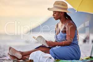 Saying no to the noise today. a beautiful young woman relaxing with a book at the beach.