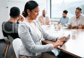 Strategic meeting in progress. an attractive young businesswoman attending a meeting in the boardroom with her colleagues in the background.