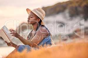 Travelling alone, dont need no baggage. a beautiful young woman relaxing with a book at the beach.