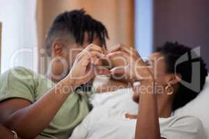 Love is more than a feeling with you. two young people making a heart gesture with their hands at home.