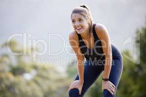 Cardio just makes you feel good. a sporty young woman catching her breath while exercising outdoors.