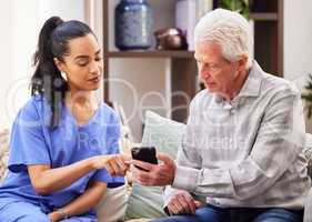 Will you help me work this thing. a young woman helping her elderly patient use a smartphone.