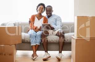 Our connection is stronger than wifi. a young couple sitting on the couch while using a digital tablet at home.