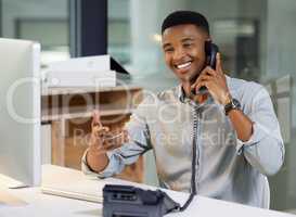 Thats what we love to hear. a young man using a telephone and computer in a modern office.