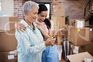 Your belongings might leave home but your heart never will. a senior woman looking at a photograph with her daughter while packing boxes on moving day.