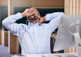 Its clearly been a long day. a young businessman yawning in an office at work.