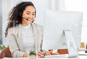 Efficiency and speed is what she practices. a young businesswoman wearing a headset while working on a computer in an office.