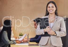 I love these meetings. Cropped portrait of an attractive young businesswoman standing with a clipboard in the boardroom with her colleagues in the background.