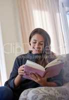 A book is a gift you can open again and again. a young woman reading a book at home.