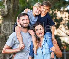 Child who lives with security, learns to have faith. Portrait of a beautiful family with their sons on their shoulders in a park.