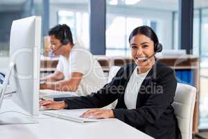 Leave the resolving of issues to us. two young businesspeople sitting in the office together and wearing headsets while using computers.