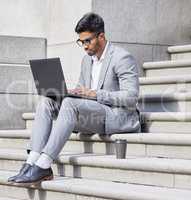 Getting productive in the city. a young man using a laptop in the city.