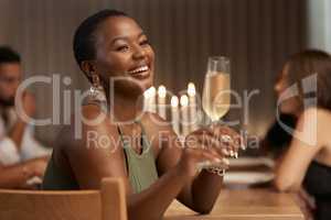 This good mood was sponsored by bubbly. an attractive young woman sitting with her friends during a dinner party and enjoying a glass of champagne.