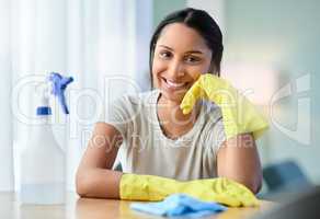 A dirty house just means youre living life right. a young woman wearing gloves at home.