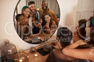 Mirror selfies will never get old. a young group of friends using a cellphone to take mirror selfies during a New Years dinner party.