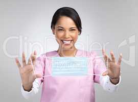 Use your mask everyday. Cropped portrait of an attractive young female healthcare worker holding up a mask in studio against a grey background.