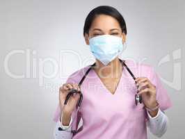 Im here for any and all ailments. Cropped portrait of an attractive young female healthcare worker wearing a mask and stethoscope while standing in studio against a grey background.