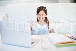 Just smile and wave. a little girl using a laptop at home.