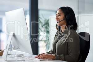 We have a team of experts waiting for your call. a woman wearing a headset while looking at her desktop in a call centre.