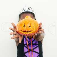 How did I do. an unrecognizable little girl covering her face with a jack o lantern against a white background.
