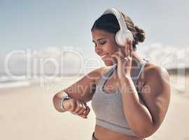 A little progress is better than no progress at all. a young woman wearing a smartwatch and headphones while out for a run.