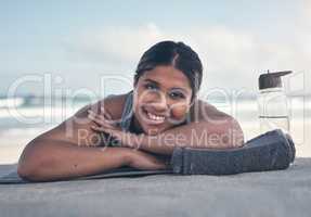 I feel super relaxed after that workout. a sporty young woman lying on her yoga mat at the beach.