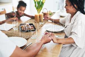 Blessing the meal that has been prepared. an unrecognizable family holding hands during prayer time at home.