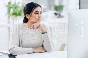 Success in business is about setting goals and achieving them. a young businesswoman looking thoughtful while working on a computer in an office.